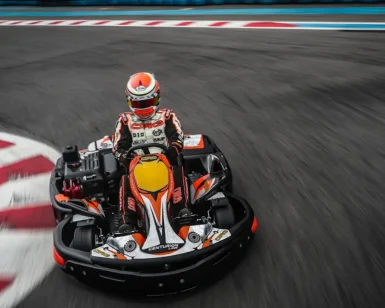 Vestido con ropa de carreras, una persona maniobra hábilmente un kart en la pista de Karting en Tenerife Sur (Los Cristianos), deslizándose rápidamente por los bordillos rojos y blancos. - ForTwo - Planes para parejas