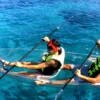 Dos personas con chalecos salvavidas realizan la excursión "Kayak Transparente en Radazul: Explora el fondo marino de Tenerife", deslizándose sobre vibrantes aguas azules sobre un impresionante paisaje submarino bajo un cielo soleado. - ForTwo - Planes para parejas