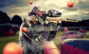En medio del vibrante caos de las bolas de pintura voladoras, un jugador completamente equipado navega con destreza los desafiantes obstáculos en los dinámicos 5 Campos Tematizados de Mallorca Paintball, apuntando con precisión. - ForTwo - Planes para parejas