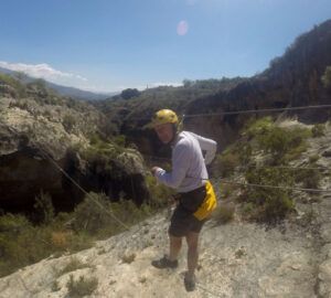 Con casco y arnés, alguien cruza valientemente el puente de cuerda de un cañón en un día soleado en el Barranco de la Luna, ideal para los amantes de la Multiaventura en el Barranco de la Luna. - ForTwo - Planes para parejas