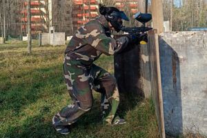 Ataviado con equipo de camuflaje, un jugador se agacha detrás de una barrera de madera con puntería precisa durante un intenso partido. Paintball en Jaca: Diversión y Estrategia en Escenarios de Alto Nivel promete una experiencia inolvidable. - ForTwo - Planes para parejas