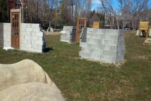 Sumérgete en una emocionante aventura con "Paintball en Jaca: Diversión y Estrategia en Escenarios de Alto Nivel", con paredes de ladrillo parciales y marcos de puertas sobre césped exuberante, que prometen emoción y juego estratégico en un entorno inspirado en Jaca. - ForTwo - Planes para parejas