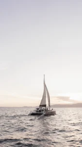 Un recorrido al atardecer en Mallorca, "Paseo en Barco al Atardecer en Mallorca", presenta un velero con gente disfrutando de un viaje tranquilo en el mar en calma bajo un cielo nublado por la noche. - ForTwo - Planes para parejas