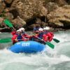 Los aventureros se enfrentan a emocionantes corrientes fluviales en balsas de un azul brillante con Sarratillo, mientras su risa resuena en el impresionante paisaje de Huesca en el Pirineo Aragonés durante "Rafting en Huesca: Aventura y Diversión. - ForTwo - Planes para parejas