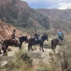 Tres ciclistas en un sendero rocoso de Sierra Nevada disfrutan del encanto de Rutas a Caballo en Granada por Sierra Nevada bajo un cielo parcialmente nublado. - ForTwo - Planes para parejas