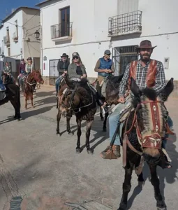 Los jinetes de las Rutas a Caballo en Granada por Sierra Nevada recorren calles de pueblos soleados con edificios blancos, con el hermoso telón de fondo de la Sierra Nevada de Granada. - ForTwo - Planes para parejas