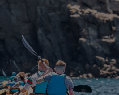 Los kayakistas con chalecos azules disfrutan de una soleada aventura de safari, remando cerca de acantilados rocosos en el "Safari en Kayak y Snorkel en Tenerife". - ForTwo - Planes para parejas