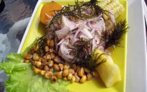 Un vibrante plato de ceviche incluye maíz, batata, lechuga, algas secas y granos de maíz tostados en un plato amarillo de Taller Cocina del Mundo: Sabores Latinoamericanos. - ForTwo - Planes para parejas
