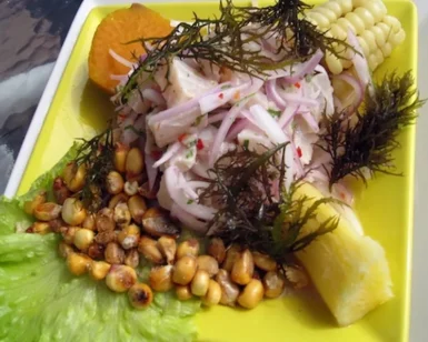 Un vibrante plato de ceviche incluye maíz, batata, lechuga, algas secas y granos de maíz tostados en un plato amarillo de Taller Cocina del Mundo: Sabores Latinoamericanos. - ForTwo - Planes para parejas