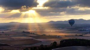 Experimente la magia de Vuelo en Globo en Mallorca desde Manacor, sobrevolando los paisajes de Mallorca al atardecer, mientras los rayos del sol se filtran entre las nubes. Disfrute de vistas impresionantes y capture el encanto de Manacor desde un mirador sereno. - ForTwo - Planes para parejas