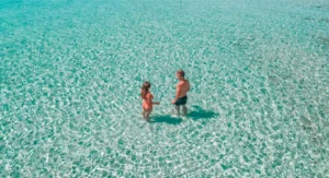 Dos personas disfrutando de las aguas turquesas de Formentera bajo el sol, vistas desde arriba: una escena sacada de "Watersports en Ibiza y Formentera: Experiencia VIP". - ForTwo - Planes para parejas