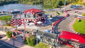 Vista aérea de AcuaKart en Sanxenxo: pista de Carreras de motos de agua, que muestra un edificio con techo rojo, asientos al aire libre y visitantes disfrutando del área. - ForTwo - Planes para parejas