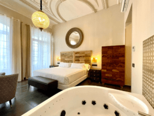 Disfrute de un elegante dormitorio con una cama grande, un espejo ornamentado, una lámpara de araña y un jacuzzi en la habitación en el Hotel con encanto en el centro de Badajoz, una mezcla perfecta de encanto y lujo. - ForTwo - Planes para parejas