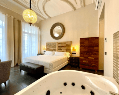 Disfrute de un elegante dormitorio con una cama grande, un espejo ornamentado, una lámpara de araña y un jacuzzi en la habitación en el Hotel con encanto en el centro de Badajoz, una mezcla perfecta de encanto y lujo. - ForTwo - Planes para parejas