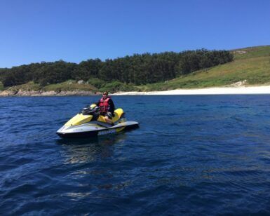 Alguien conduce una moto de agua amarilla por las cristalinas aguas azules cerca de la exuberante costa de Vilagarcía de Arousa bajo un cielo azul. ¡Alquila tu moto de agua en Vilagarcía de Arousa hoy!. - ForTwo - Planes para parejas