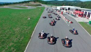 Vista aérea de las emocionantes "Carreras de karts en el Kartódromo Valga en Pontevedra", que muestran a varios pilotos corriendo a lo largo de la pista junto a un edificio y amplios campos verdes. - ForTwo - Planes para parejas