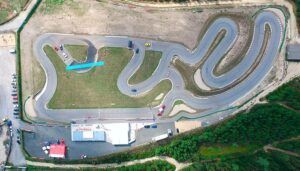 Los intrincados caminos de una pista de karts serpentean por el paisaje, rodeados de edificios y coches aparcados. Aquí es donde "Carreras de karts en el Kartódromo Valga en Pontevedra" da vida a la emocionante velocidad. - ForTwo - Planes para parejas