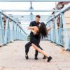 Una pareja baila apasionadamente en un puente peatonal al aire libre en Vigo, integrándose maravillosamente con el entorno urbano, inspirado en "Clases de Salsa y Bachata en Vigo". - ForTwo - Planes para parejas