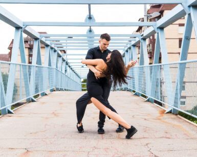 Una pareja baila apasionadamente en un puente peatonal al aire libre en Vigo, integrándose maravillosamente con el entorno urbano, inspirado en "Clases de Salsa y Bachata en Vigo". - ForTwo - Planes para parejas