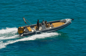 En una lancha neumática gris sobre aguas cristalinas, dos personas disfrutan de una emocionante aventura que recuerda a un tour de Excursión 4x4, senderismo y barco en Ibiza. - ForTwo - Planes para parejas