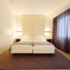 Experimente la tranquila elegancia del dormitorio minimalista del Hotel Lois en A Coruña con dos camas individuales, una alfombra grande, cortinas marrones, iluminación suave en una pared con acento de madera: un santuario ideal para la relajación. - ForTwo - Planes para parejas