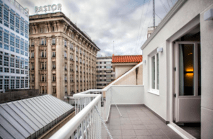 La terraza de la azotea del Hotel Lois en A Coruña, con su barandilla blanca, ofrece impresionantes vistas del horizonte de la ciudad bajo un espectacular cielo nublado. - ForTwo - Planes para parejas