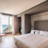 Alójese en el Hotel Riazor en La Coruña y disfrute de una moderna habitación con una cama grande, escritorio y TV. Cortinas transparentes enmarcan impresionantes vistas al mar para una experiencia encantadora desde su ventana. - ForTwo - Planes para parejas