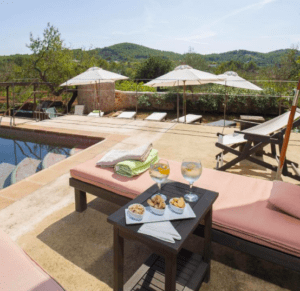 El Hotel Rural: Escapada al corazón de Ibiza cuenta con una pintoresca zona de piscina con tumbonas, sombrillas y una mesa de aperitivos y bebidas, perfecta para su próxima escapada. - ForTwo - Planes para parejas