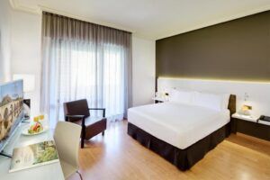 Explore el Hotel en el Corazón Badajoz, un santuario refinado con una cama grande y cómoda, un elegante escritorio con silla y un televisor moderno. Sus elegantes ventanales le invitan a relajarse en el corazón de Badajoz. - ForTwo - Planes para parejas