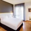 Disfrute del encanto acogedor de su moderna habitación en el Hotel en el Corazón Badajoz, equipada con una cama grande, escritorio, silla, lámparas de pared y una ventana con cortinas transparentes. El elegante suelo de madera realza este acogedor refugio. - ForTwo - Planes para parejas