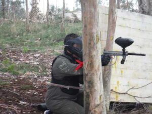 En la zona boscosa de A Coruña, alguien disfruta de "La mejor experiencia de paintball en A Coruña", agazapado detrás de un árbol y apuntando con destreza su marcadora. - ForTwo - Planes para parejas