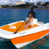 Dos personas se relajan en un barco naranja y blanco en las aguas cristalinas de una orilla de arena, abrazando el espíritu de "Navega Ibiza a tu Ritmo: Barcos sin Licencia" mientras exploran sin límites. - ForTwo - Planes para parejas
