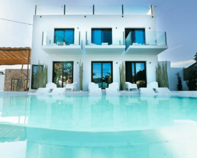 Esta moderna villa blanca, con amplios ventanales y balcones, ofrece vistas a una piscina cristalina y un remanso de paz. Combinando lujo y relajación bajo un cielo azul despejado, evoca la esencia de PAIISE Hotels Ibiza: Relájate cerca de las playas. - ForTwo - Planes para parejas