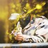 En los emocionantes campos de batalla de Pontevedra, un jugador se pone equipo de camuflaje y máscara para una intensa ronda de Paintball "El Superviviente", disparando una pistola de paintball mientras pintura amarilla vibrante salpica alrededor. - ForTwo - Planes para parejas