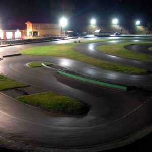 Por la noche, la pista de karts vacía de Vive la velocidad en el Karting Soto de Dueñas, Asturias, muestra caminos de asfalto sinuosos e iluminados y áreas verdes, capturando una serena sensación de velocidad. - ForTwo - Planes para parejas