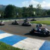 En Karting Soto de Dueñas, Asturias, los competidores compiten con maestría en karts en una pista con bordes azules y blancos, rodeada de frondosos árboles y montañas impresionantes. Experimenta la emoción de "Vive la velocidad". - ForTwo - Planes para parejas