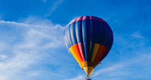 El "Vuelo en Globo en Badajoz al amanecer" ofrece una experiencia impresionante mientras un vibrante globo aerostático se desliza elegantemente contra el cielo azul brillante, ofreciendo vistas impresionantes de Badajoz. - ForTwo - Planes para parejas