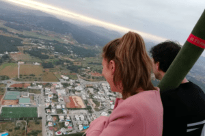 Dos personas se maravillan con los campos y edificios de abajo durante el amanecer en "Vuelo en globo: Ibiza desde las alturas al amanecer", mientras tonos suaves pintan el paisaje de Ibiza. - ForTwo - Planes para parejas