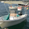 Una pequeña lancha con toldo está fondeada en el puerto de Mallorca, con un cartel de "Se alquila". Es perfecta para quienes buscan "Barco sin licencia en Mallorca", con varias otras embarcaciones visibles al fondo. Ideal para los amantes del alquiler de barcos. - ForTwo - Planes para parejas