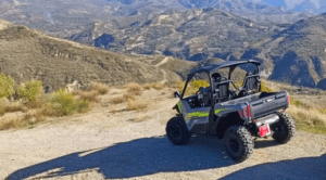 An Aventura en Buggy Biplaza en Granada está estacionada en un camino de tierra frente a las escarpadas montañas y el cielo azul claro, prometiendo una emocionante aventura en la naturaleza. - ForTwo - Planes para parejas