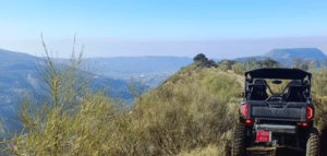 Experimente una Aventura en Buggy Biplaza en Granada en un sendero de montaña accidentado, que ofrece vistas de colinas distantes y un pueblo en el impresionante paisaje bajo un cielo azul claro. - ForTwo - Planes para parejas