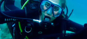 Un buceador con el kit de Bautismo de Buceo en Mallorca explora aguas turquesas, totalmente equipado con máscara y equipo de respiración. - ForTwo - Planes para parejas