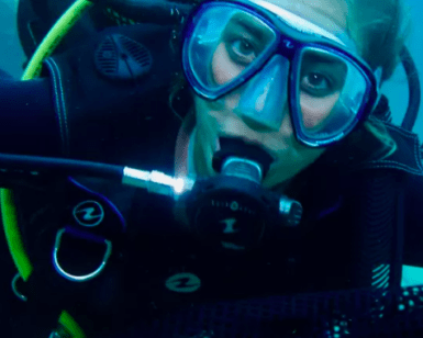 Un buceador con el kit de Bautismo de Buceo en Mallorca explora aguas turquesas, totalmente equipado con máscara y equipo de respiración. - ForTwo - Planes para parejas