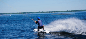 Participando en una Clase Privada de Wakeboard, alguien practica wakeboard con destreza en el lago. Con casco de seguridad, crea un impresionante chapuzón bajo el cielo azul despejado. - ForTwo - Planes para parejas
