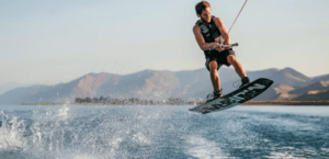 Durante una sesión de Clase Privada de Wakeboard, un entusiasta maniobra hábilmente sobre aguas resplandecientes, con majestuosas montañas elevándose en el fondo. - ForTwo - Planes para parejas