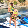 Dos personas con chalecos salvavidas exploran las cristalinas aguas azules cerca de los acantilados rocosos de Mallorca utilizando "Descubre Mallorca en Moto de Agua". - ForTwo - Planes para parejas