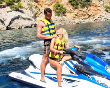 Dos personas con chalecos salvavidas exploran las cristalinas aguas azules cerca de los acantilados rocosos de Mallorca utilizando "Descubre Mallorca en Moto de Agua". - ForTwo - Planes para parejas