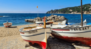 Experimente el encanto de la playa de arena y la costa rocosa de Girona, con sus barcos de pesca y un vasto mar azul bajo un cielo despejado. Descubra los susurros de la historia en sus calles adoquinadas con "Descubre Pueblos Medievales desde Girona". - ForTwo - Planes para parejas