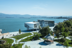 Este moderno edificio frente al mar, que recuerda al impresionante "Descubre el Centro Botín", cuenta con un tranquilo parque, un encantador mirador y colinas distantes bajo un cielo azul claro. - ForTwo - Planes para parejas