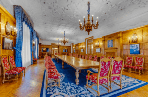 Explore un comedor que refleja la grandeza del Palacio de la Magdalena, con una larga mesa de madera, sillas con estampados rojos, elegantes candelabros y vibrantes cortinas azules: una elección natural para aquellos que tienen buen ojo para la elegancia. - ForTwo - Planes para parejas